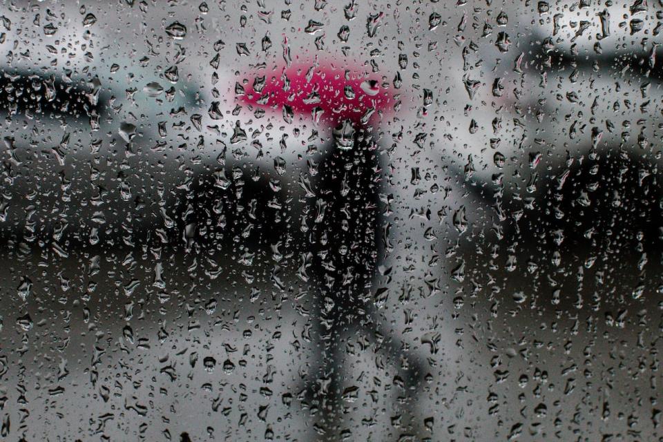 A man walks down a sidewalk carrying an umbrella during a period of heavy rain in Surrey, British Columbia on Tuesday, January 12, 2022. 