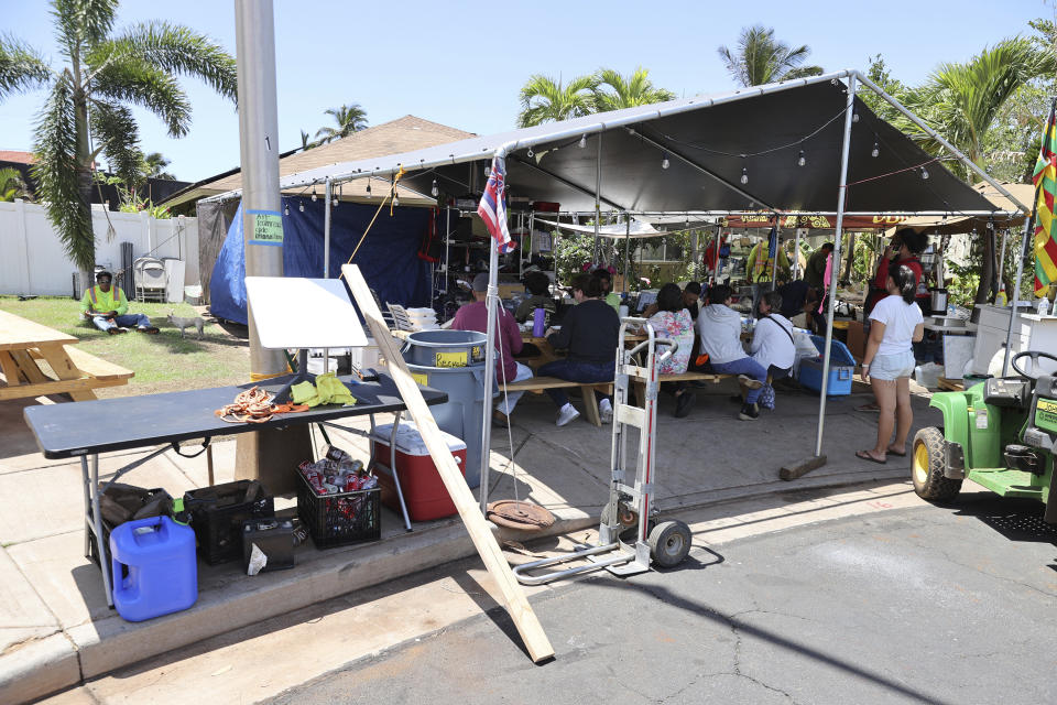 Volunteers gather outside a house in a Hawaiian Homestead community that’s serving as a fire-relief distribution hub in Lahaina, Hawaii, on Friday, Sept. 1, 2023. The Villages of Leiali'I, a Native Hawaiian neighborhood, lost only two out of 104 houses in a deadly August blaze. (AP Photo/Marco Garcia)