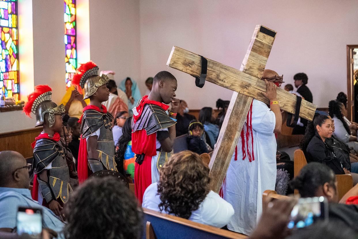 Rev. Fred Booker, dressed as Jesus, carries a cross through the aisle of Family Missionary Baptist Church where he is an associate minister as performers dressed as soldiers follow him during a special Easter performance held Palm Sunday, March 24, at the church in Columbus' Southern Orchards neighborhood. The special performance reenacted several scenes from the Last Supper, crucifixion and resurrection of Jesus.