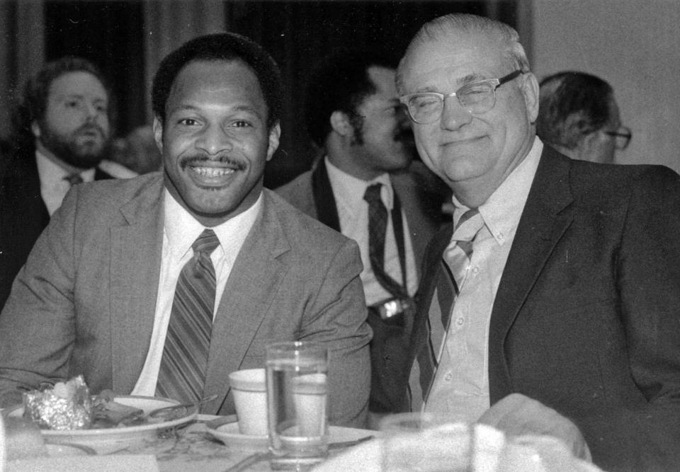 Archie Griffin, left, and ex-coach Woody Hayes share some conversation at dinner table in 1983.