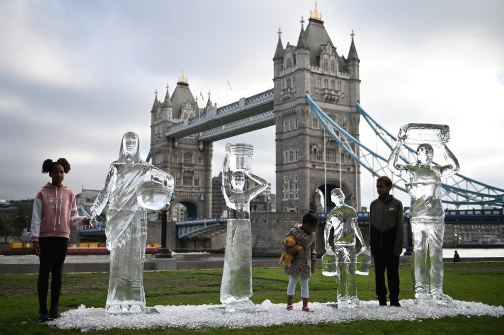 Children pose by ice sculptures depicting people collecting water by charity Water Aid to show the fragility of water and the threat posed by climate change in London (AFP/Getty)