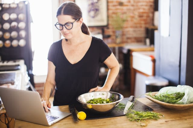 Woman on laptop computer in her home kitchen