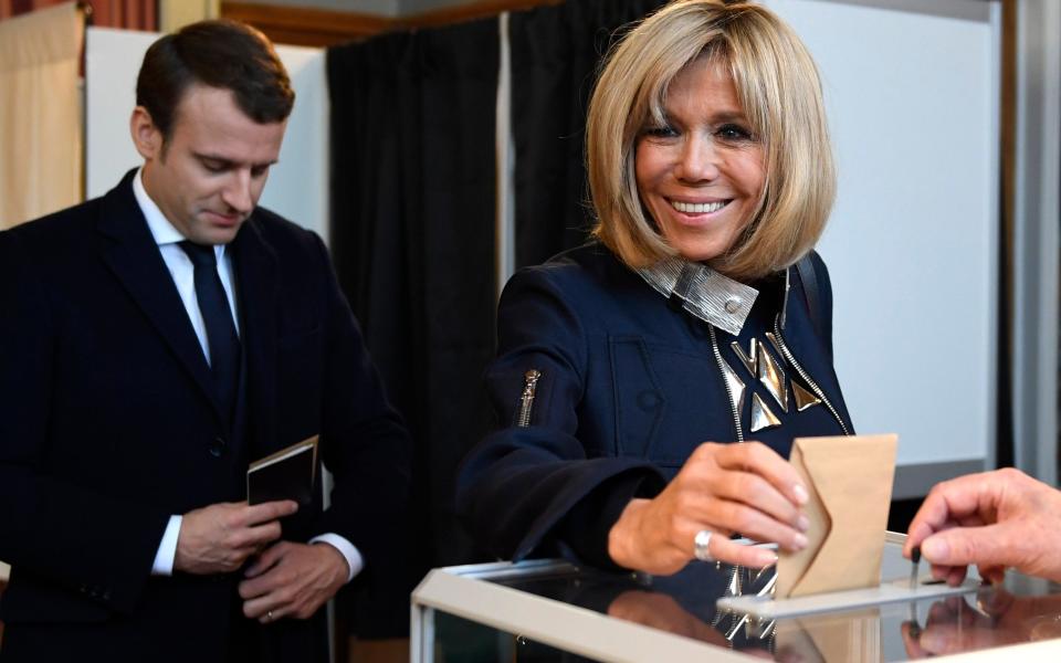 French presidential election candidate for the 'En Marche!' (Onwards!) political movement, Emmanuel Macron (L) looks on as his wife Brigitte Trogneux (R) casts her ballot at a polling station in Le Touquet, northern France - Credit: EPA