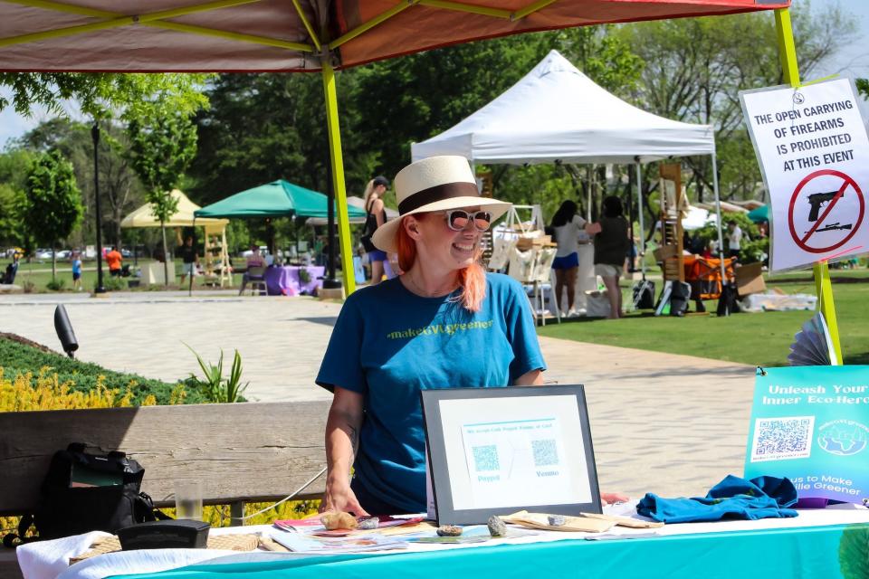 Founder and Executive Director of environmental organization Make GVL Greener smiles as a person walks toward the Earth Day Festival in Unity Park on April 20. This is the second year of the festival.