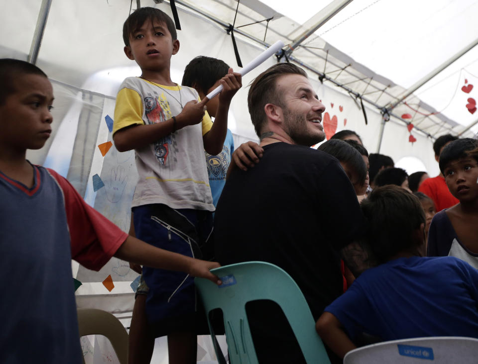 Former England soccer team captain David Beckham interacts with typhoon survivors during his visit to Typhoon Haiyan-hit Tacloban city, central Philippines, Thursday, Feb. 13, 2014. Beckham visited the storm-devastated Philippine city as part of UNICEF's relief efforts. (AP Photo/Bullit Marquez)