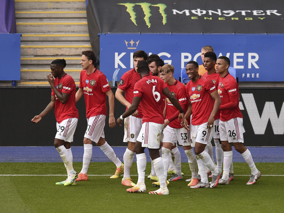 Manchester United's Bruno Fernandes celebrates with teammates after scoring his side's opening goal from the penalty spot during the English Premier League soccer match between Leicester City and Manchester United at the King Power Stadium, in Leicester, England, Sunday, July 26, 2020. (Oli Scarff/Pool via AP)