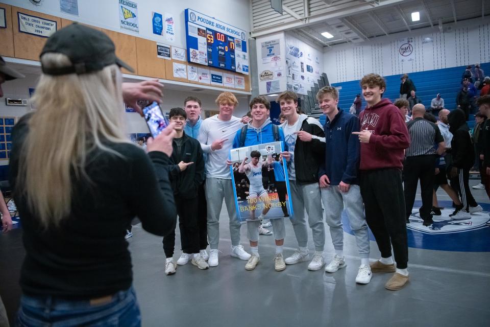 Linda Norby takes a photo of Poudre wrestler Banks Norby holding a poster celebrating 100 wins after he defeated Fort Collins' Tristan Anthony during a wrestling dual on Thursday, January 18, 2024 at Poudre High School in Fort Collins, Colo.