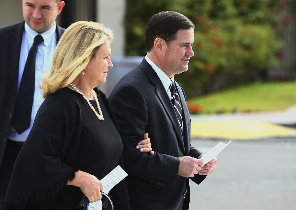 Arizona Republican Gov. Doug Ducey, right, is joined by his wife Angela as they arrive for the funeral of former Democratic U.S. Rep. Ed Pastor Friday, Dec. 7, 2018, in Phoenix. Pastor was Arizona's first Hispanic member of Congress, spending 23 years in Congress before retiring in 2014. Pastor passed away last week at the age of 75. (AP Photo/Ross D. Franklin)