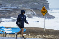 A man walks along the beach front at Bronte Beach as rain continues to fall in Sydney, Australia, Wednesday, July 6, 2022. More than 50,000 residents of Sydney and its surrounds have been told to evacuate or prepare to abandon their homes on Tuesday as Australia's largest city braces for what could be its worst flooding in 18 months. (AP Photo/Mark Baker)