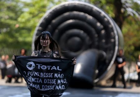 FILE PHOTO: A Greenpeace activist holds a sign during a protest to defend the Amazon reef outside the French oil company Total's headquarters in Rio de Janeiro, Brazil September 28, 2017. The sign reads: "Total, the people say no, science says no, Ibama (Brazilian Institute of the Environment and Renewable Natural Resources) says no." REUTERS/Pilar Olivares