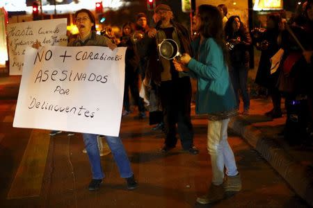 A woman holds up a placard that reads "No more policemen murdered by delinquents" as they beat cooking utensils during a rally against what rally participants say is an explosion in crime, Santiago, Chile, July 29, 2015. REUTERS/Ivan Alvarado