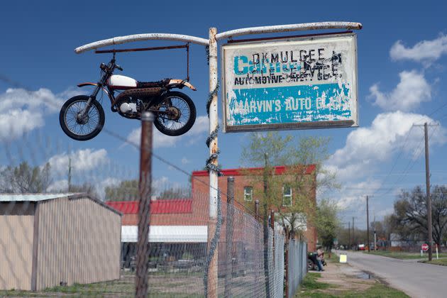 A motorbike is suspended in the air as part of the sign for an auto-body shop on Oklahoma Avenue in Okmulgee.