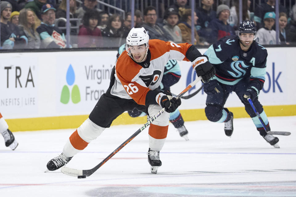 Philadelphia Flyers defenseman Sean Walker (26) skates with the puck with Seattle Kraken right wing Jordan Eberle (7) trailing during the second period of an NHL hockey game, Friday, Dec. 29, 2023, in Seattle. (AP Photo/John Froschauer)