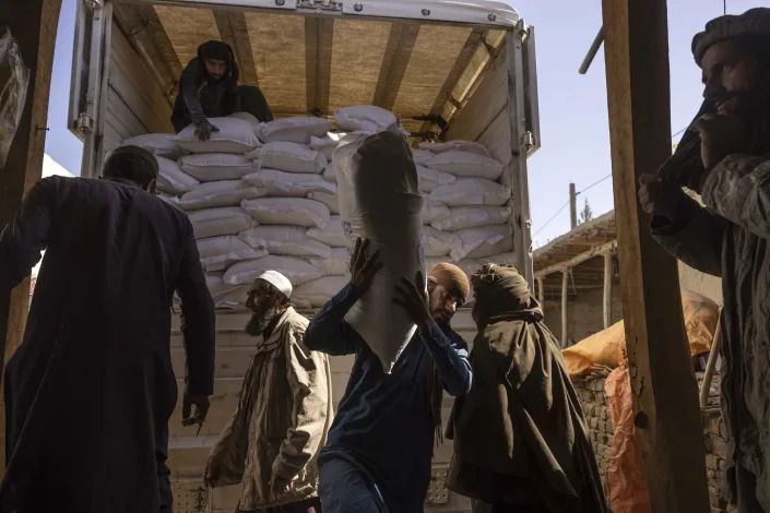 Laborers unload sacks of flour from a World Food Program convoy that traveled from Kabul to Afghanistan's Tagab district, Oct. 27, 2021. (Victor J. Blue/The New York Times)