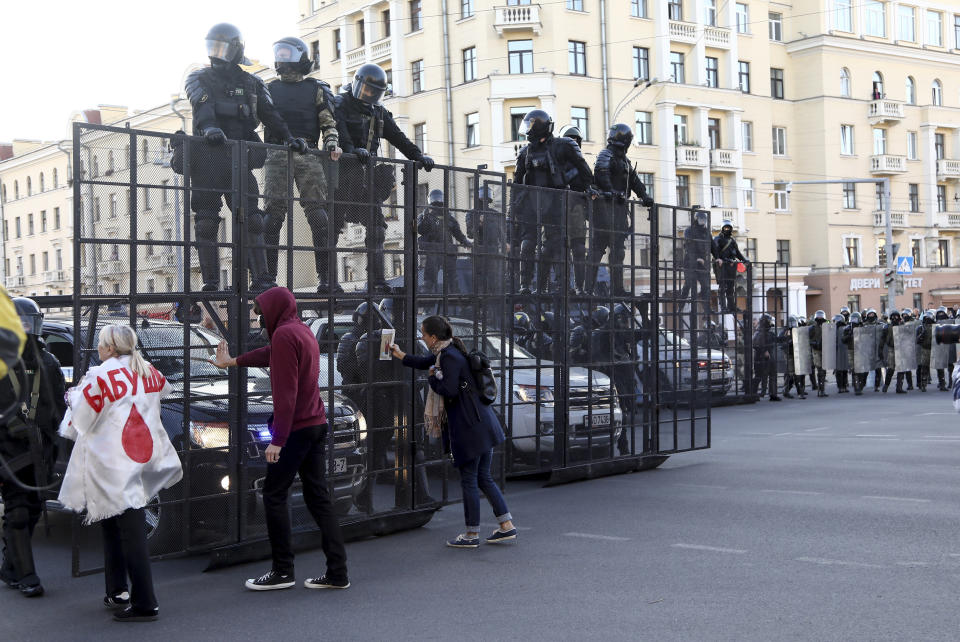 Protesters try to speak to police as they block the road to prevent against an opposition rally to protest the official presidential election results in Minsk, Belarus, Sunday, Sept. 20, 2020. Tens of thousands of Belarusians calling for the authoritarian president to resign marched through the capital on Sunday as the country's wave of protests entered its seventh week. Hundreds of soldiers blocked off the center of Minsk, deploying water cannon and armored personnel carriers and erecting barbed wire barriers. (AP Photo/TUT.by)