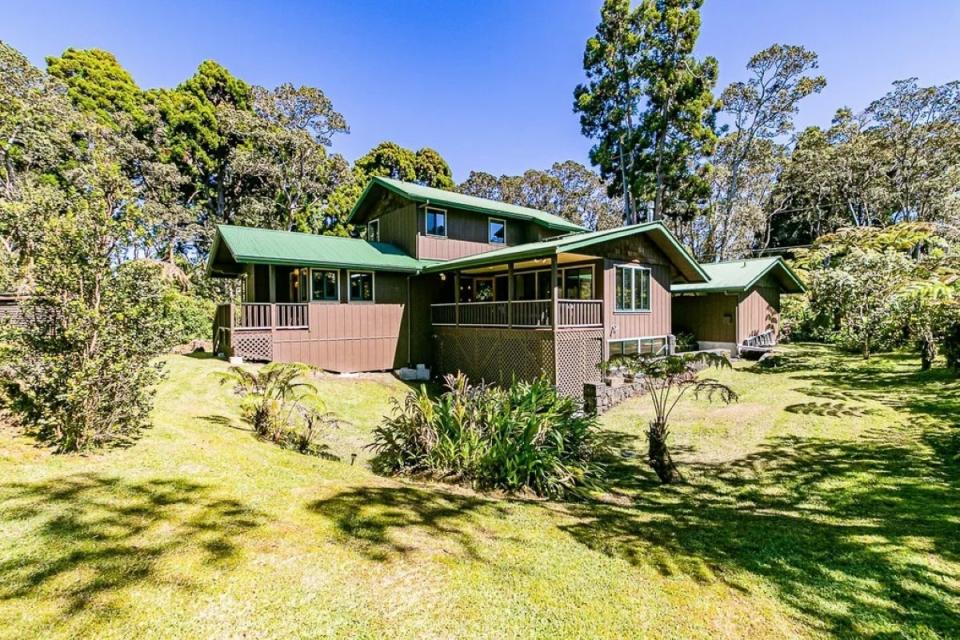 Brown house with green roof around green forest