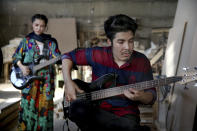 In this July 26, 2018 photo, Afghan musicians Mohammad Rezai, right, and Soraya Hosseini, members of the Arikayn rock band, play guitar at a furniture workshop on the outskirts of Tehran, Iran. Like others in Iran's vibrant arts scene, Afghan musicians must contend with hard-liners who view Western culture as corrupt and object to women performing in public. (AP Photo/Ebrahim Noroozi)