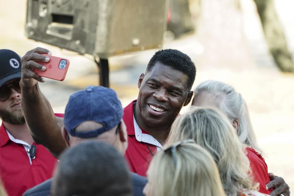 Republican candidate for U.S. Senate Herschel Walker takes photos with supporters during a campaign rally Tuesday, Nov. 29, 2022, in Greensboro, Ga. Walker is in a runoff election with incumbent Democratic Sen. Raphael Warnock. (AP Photo/John Bazemore)