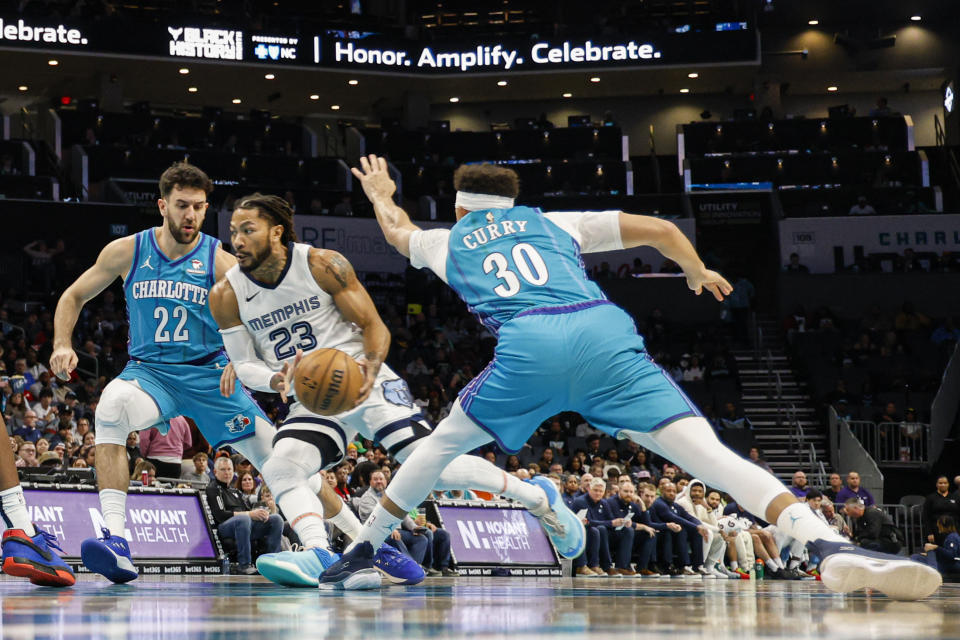 Memphis Grizzlies guard Derrick Rose (23) drives between Charlotte Hornets guards Vasilije Micic, left, and Seth Curry, right, during the first half of an NBA basketball game in Charlotte, N.C., Saturday, Feb. 10, 2024. (AP Photo/Nell Redmond)