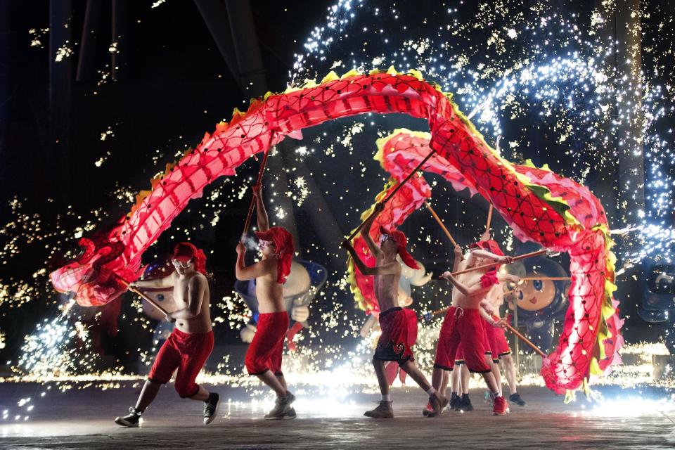 In freezing weather, shirtless men lead a dragon dance amid firecrackers during an event for the Chinese New Year. - Credit: Kyodo/AP
