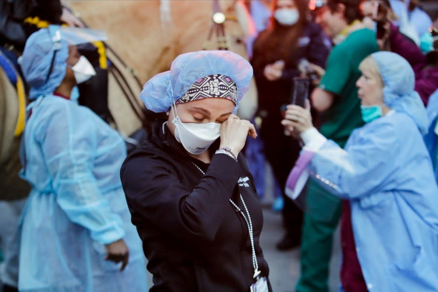 FILE – A medical worker reacts as police officers and pedestrians cheer medical workers outside NYU Medical Center in New York, April 16, 2020. Some states that stockpiled millions of masks and other personal protective equipment during the coronavirus pandemic are now throwing the items away. (AP Photo/Frank Franklin II, File)