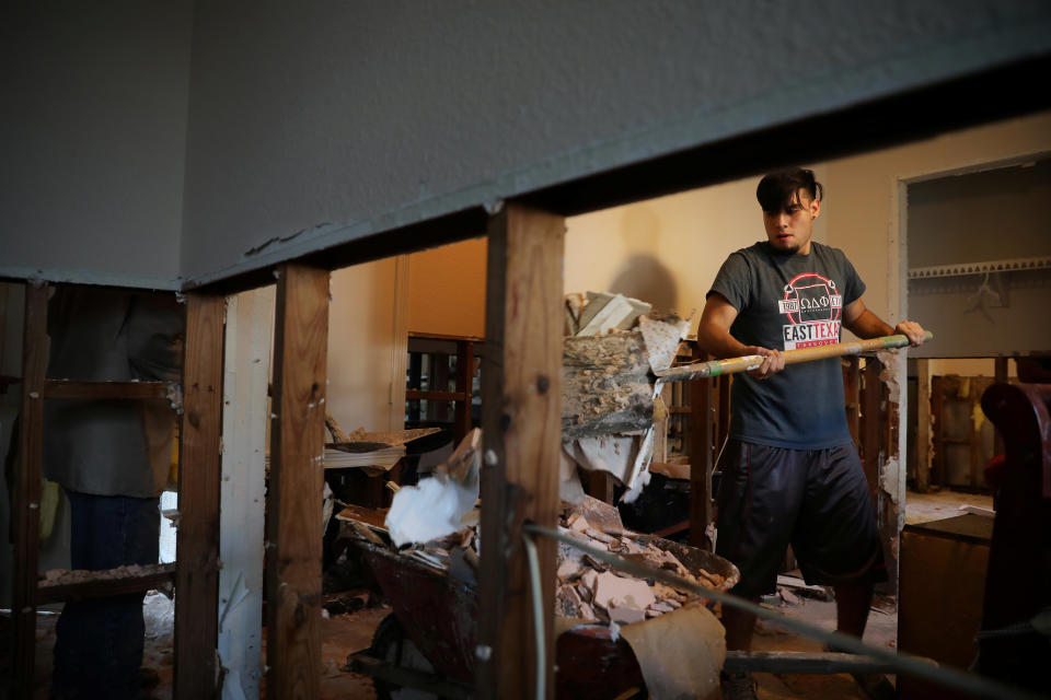 Lorenzo Salina helps a neighbor remove damaged walls.