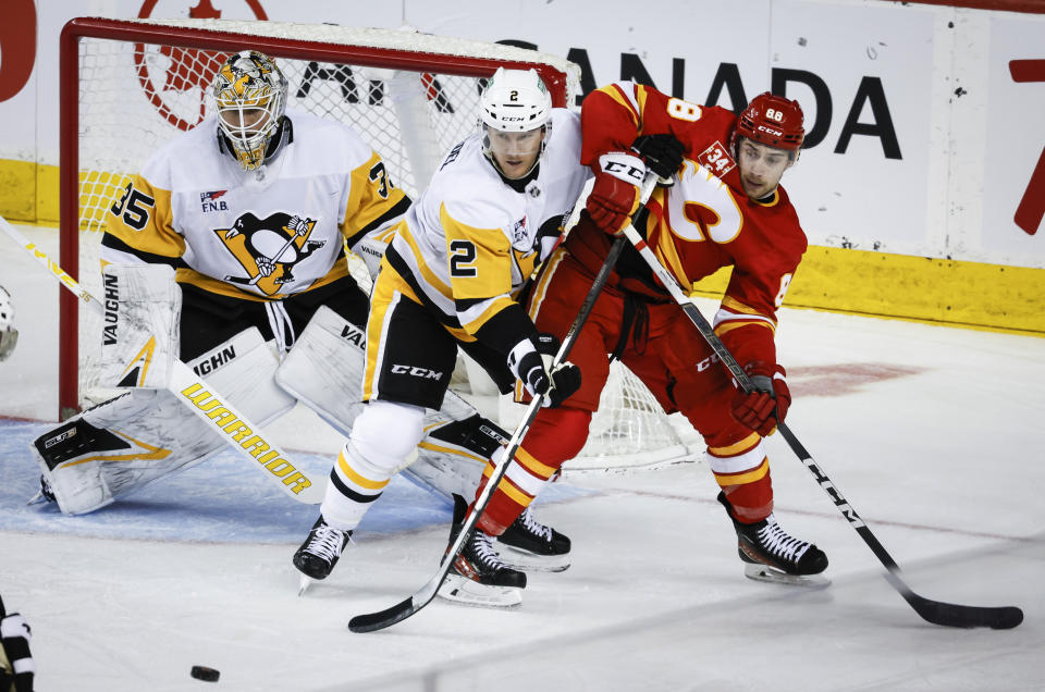 Pittsburgh Penguins defenceman Chad Ruhwedel (2) keeps Calgary Flames forward Andrew Mangiapane (88) away from goalie Tristan Jarry (35) during the second period of an NHL hockey game Saturday, March 2, 2024, in Calgary, Alberta. (Jeff McIntosh/The Canadian Press via AP)