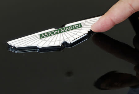 Sales Manager Raymond Liu points to an Aston Martin insignia on a car as he explains how each is handmade, at their showroom in Singapore August 1, 2014. REUTERS/Edgar Su