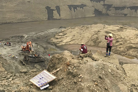 Jade miners take photos at the mud pond where more than 50 people were killed in collapse, in Hpakant, Kachin, Myanmar April 28, 2019. REUTERS/Shoon Naing