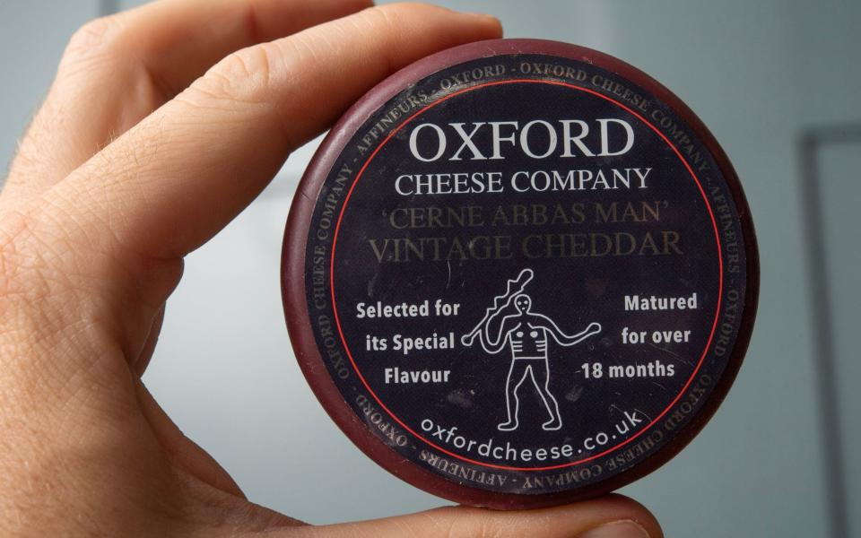 Someone holding up a wheel of the cheese with the 'castrated' Cerne Abbas giant on the packaging - BNPS