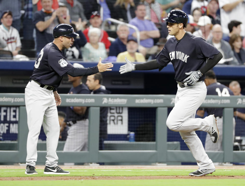 New York Yankees' Greg Bird, right, high-fives third base coach Joe Espada after hitting a two-run home run to score teammate Gary Sanchez in the third inning of an exhibition spring training baseball game against the Atlanta Braves in Atlanta, Friday, March 31, 2017. (AP Photo/David Goldman)