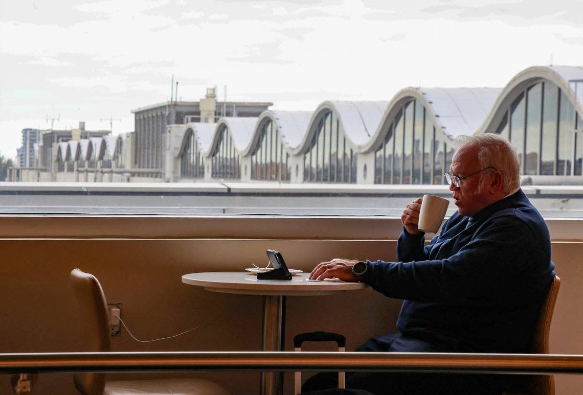 A traveler sips coffee while enjoying the large glass windows at the Delta Sky Club at MIA on Tuesday, April 9, 2024 in Miami, Florida.