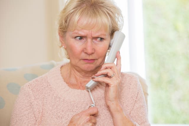 Worried Senior Woman Answering Telephone At Home