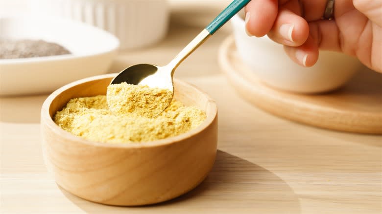 Taking a spoonful out of nutritional yeast bowl