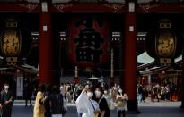 Visitors wearing protective face masks take selfie photos at Asakusa district in Tokyo