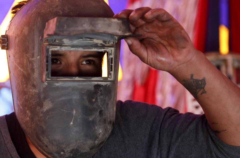 Jumbo Circus owner and acrobat Joel Condori peeks through his visor at the progress of his work while welding a part on steel structure as the circus enters its fourth month closed due to the COVID-19 lockdown in El Alto, Bolivia, Friday, June 26, 2020. Since the pandemic lockdown, Condori, 27, said five remaining circus performers work as handymen and at restaurants to earn a living, himself included. (AP Photo/Juan Karita)