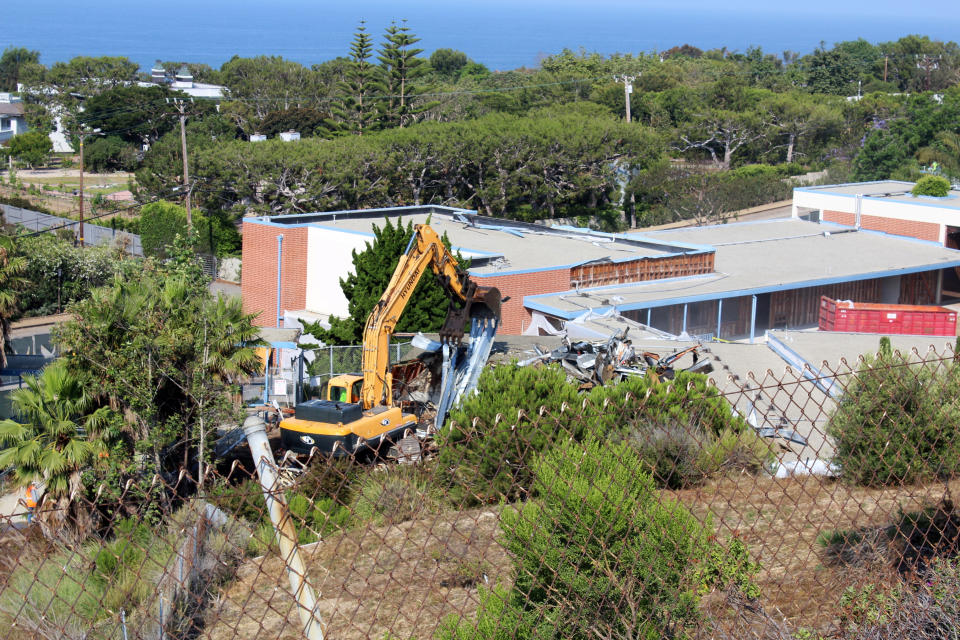 This July 5, 2017, image provided by Malibu Surfside News shows the demolition of the former Malibu Middle School in California. The school was torn down after testing found high levels of PCBs, which were used in some caulk, floor adhesive and in fluorescent light ballasts until the chemicals were banned in the late 1970s over fears that they could cause cancer. (Barbara Burke/Malibu Surfside News via AP)