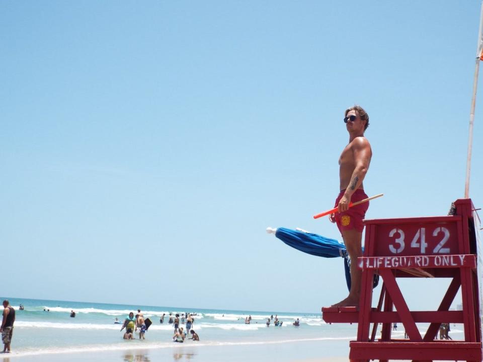 Lifeguard Ed Baker stands atop Tower 342 near Sun Splash Park at 611 S. Atlantic Avenue in Daytona Beach shortly after he and lifeguard Declan Outlaw rescued a woman caught in a rip current. As the busy July 4th weekend approaches, there are fewer lifeguards on the beach as the Volusia County Beach Safety Ocean Rescue is unable to find workers to fill 100 vacancies.