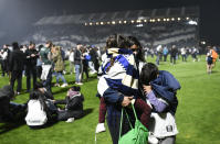 Fans of Gimnasia de La Plata react to tear gas on the field during a local tournament match between Gimnasia de La Plata and Boca Juniors in La Plata, Argentina, Thursday, Oct. 6, 2022. The match was suspended after tear gas thrown by the police outside the stadium wafted inside affecting the players as well as fans who fled to the field to avoid its effects. (AP Photo/Gustavo Garello)