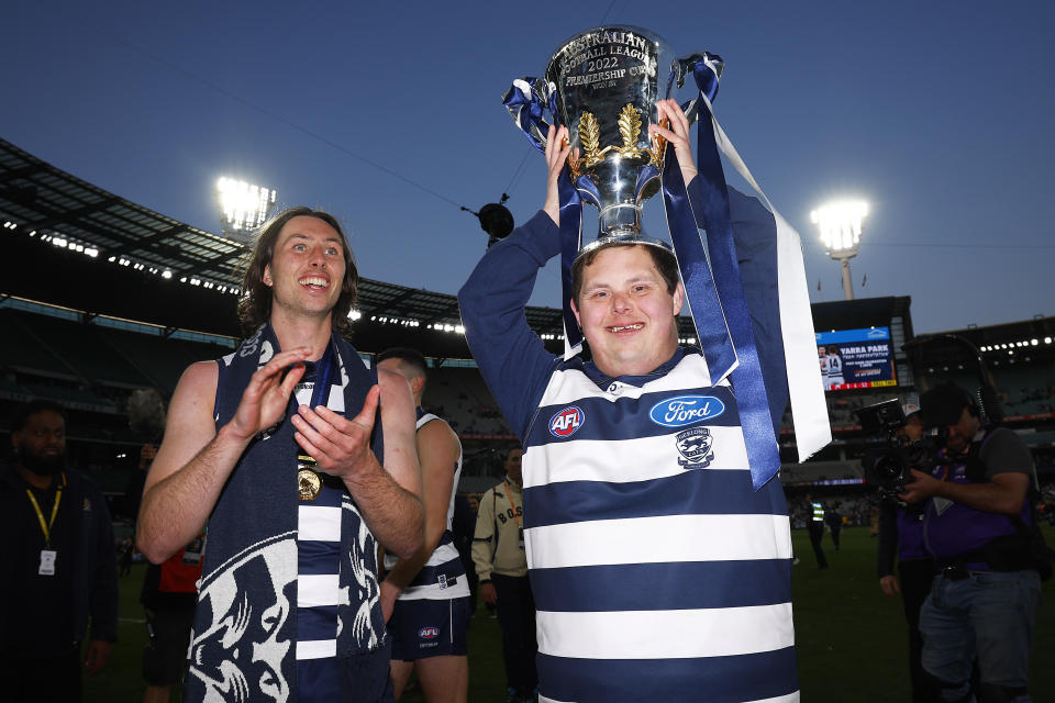 This photo shows Geelong fan Sam Moorfoot holding the AFL's premiership cup aloft after the Cats' big win over Sydney in the grand final. 