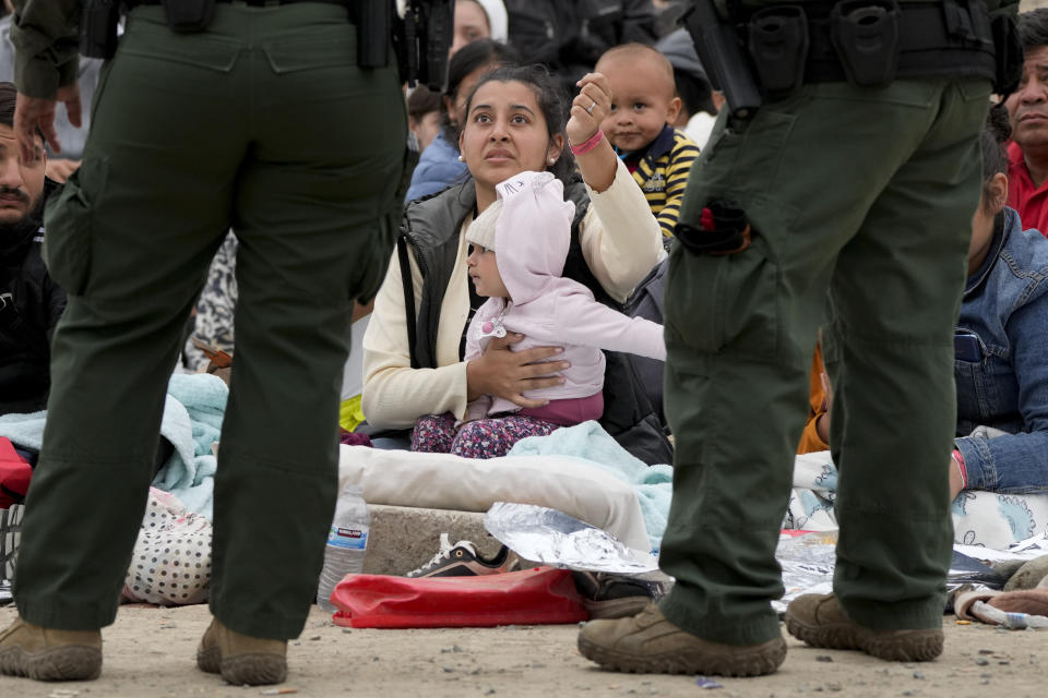 Una mujer enseña su brazalete para mostrarle a agentes de la Patrulla Fronteriza que ella y su hija llevan más tiempo aguardando entre dos muros en la frontera para solicitar asilo, el viernes 12 de mayo de 2023, en San Diego. Cientos de migrantes siguen esperando entre los dos muros, muchos de ellos desde hace días. Estados Unidos inició una nueva política de manejo de la inmigración a partir del viernes, poniendo fin a una medida que restringió el asilo durante tres años e implementando una serie de nuevas normas estrictas que el gobierno del presidente Joe Biden espera estabilizarán la frontera entre Estados Unidos y México y orillarán a los migrantes a solicitar ingresar vía internet desde el país en el que vivan, con lo que no tendrán que hacer el peligroso viaje hacia el norte. (AP Foto/Gregory Bull)