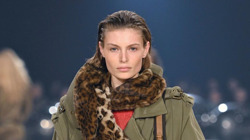 A model walks the runway during the Isabel Marant Ready to Wear Fall/Winter 2024-2025 fashion show in a matching green jacket and torusers combo with a fluffy cheetah print scarf