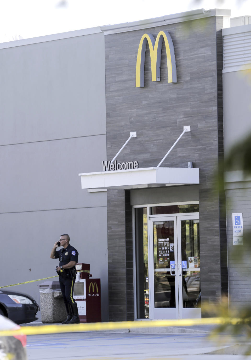 The McDonald's located on Lasalle Street in Mandeville, La., is about 100 yards from the shooting, is closed and guarded by a police officer Friday, Sept. 20, 2019. Two police officers have been shot in Louisiana, one fatally, after a vehicle chase north of New Orleans. The suspects are in custody. (David Grunfeld/The Advocate via AP)