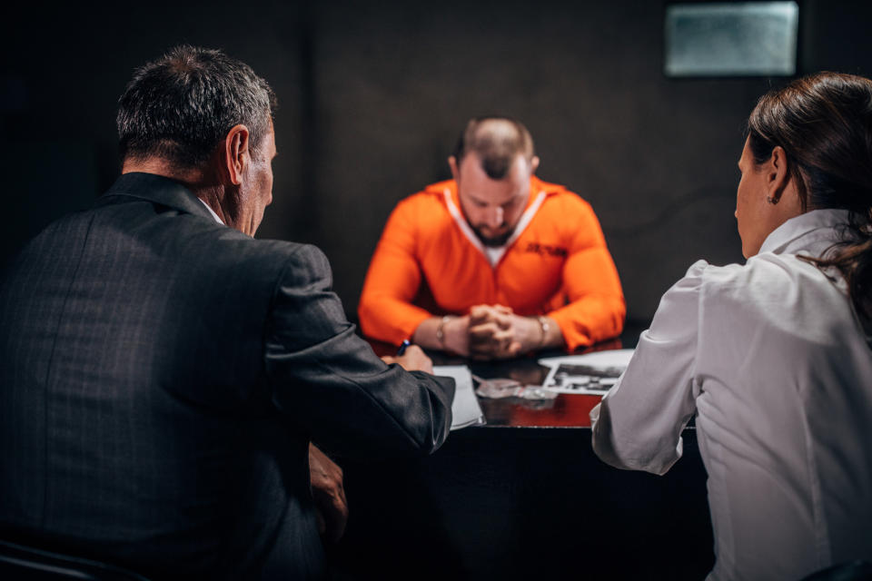 A person sitting looking down across the table from two people taking notes