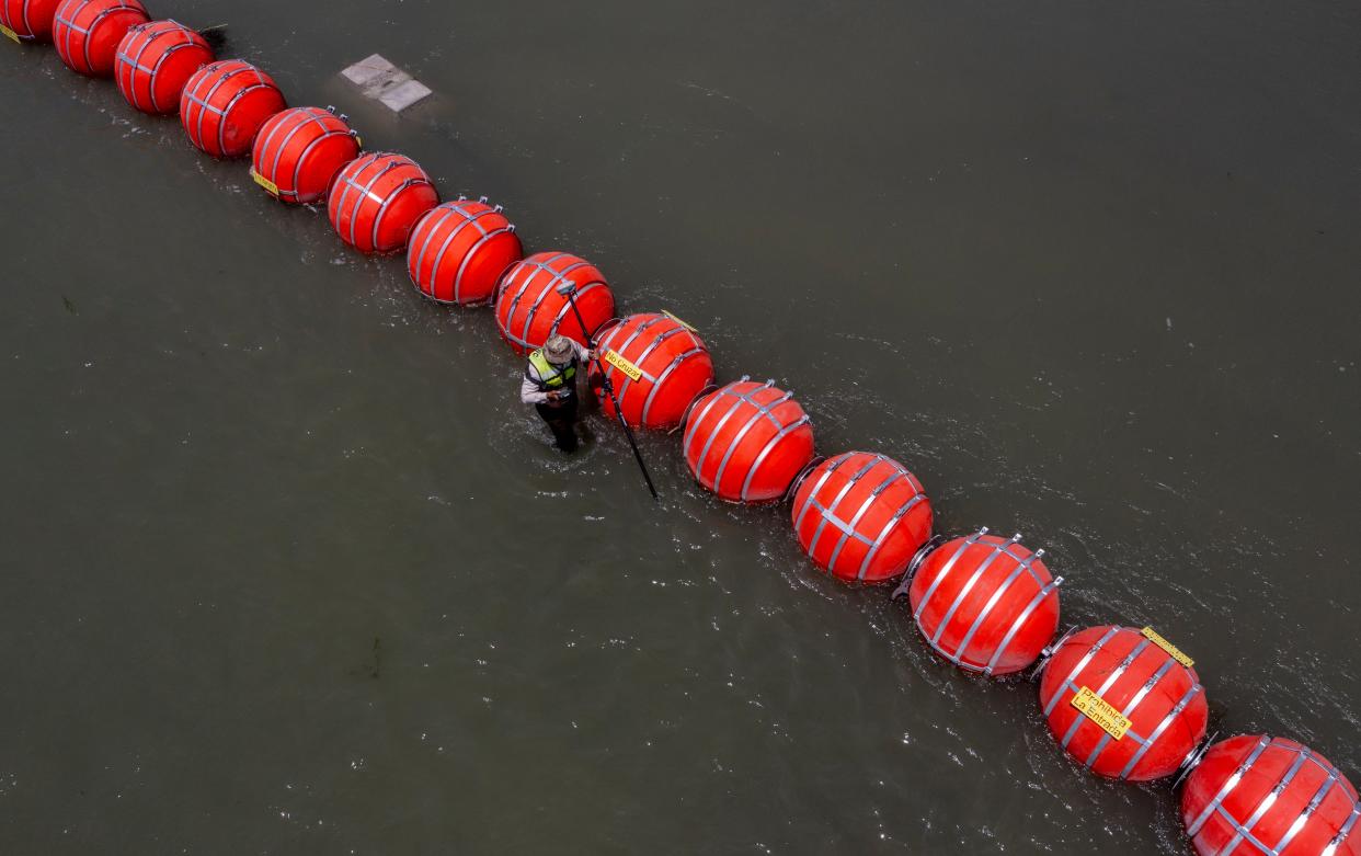 Buoys float on the Rio Grande in Eagle Pass as a Mexican engineer, center, with the International Boundary and Water Commission uses GPS on July 20 to determine if the buoys cross into Mexican territory. The commission reported that about 80% of the buoys were on Mexico's side of the river.