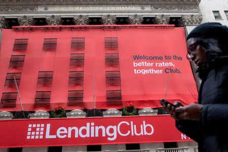 FILE PHOTO: A woman looks at her phone as she passes by a Lending Club banner on the facade of the the New York Stock Exchange December 11, 2014. REUTERS/Brendan McDermid/File Photo
