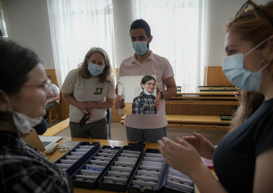 A girl is reflected in a mirror while picking the frames for her glasses during an eyesight examination performed by volunteer ophthalmologists, in Nucsoara, Romania, Saturday, May 29, 2021. (AP Photo/Vadim Ghirda)