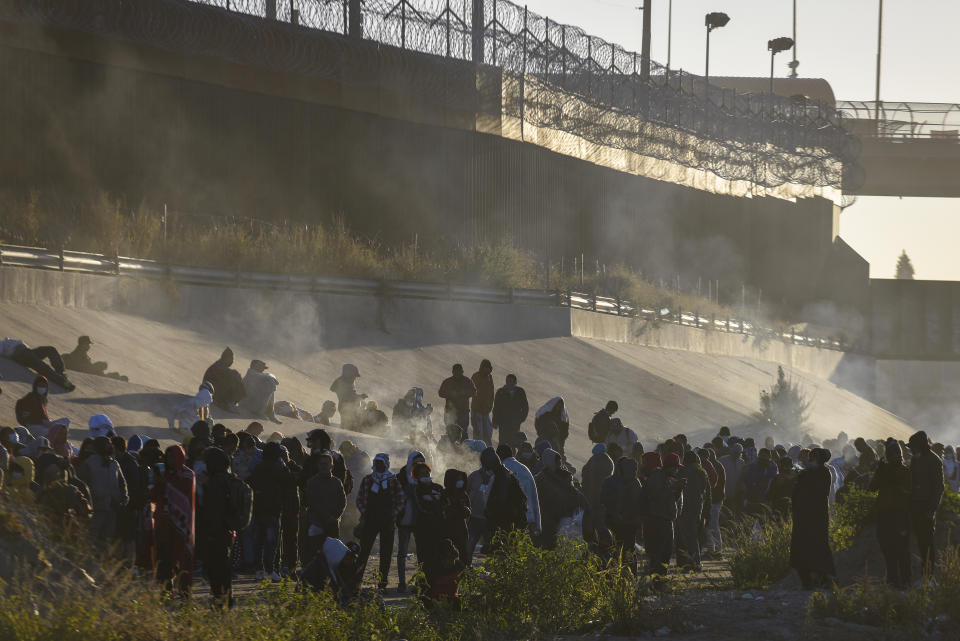 Smoke rises from small fires keeping migrants warm as they wait to cross the Mexico-U.S. border from Ciudad Juarez, Mexico, Monday, Dec. 12, 2022. According to the Ciudad Juarez Human Rights Office, hundreds of mostly Central American migrants arrived in buses and crossed the border to seek asylum in the U.S., after spending the night in shelters. (AP Photo/Christian Chavez)