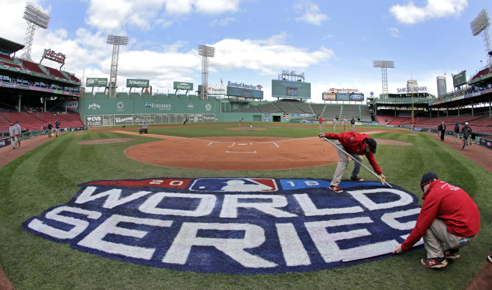 Grounds crew members paint the World Series logo behind home plate at Fenway Park, Sunday, Oct. 21, 2018, in Boston, as they prepare for Game 1 of the baseball World Series between the Boston Red Sox and the Los Angeles Dodgers scheduled for Tuesday in Boston. (AP Photo/Elise Amendola)