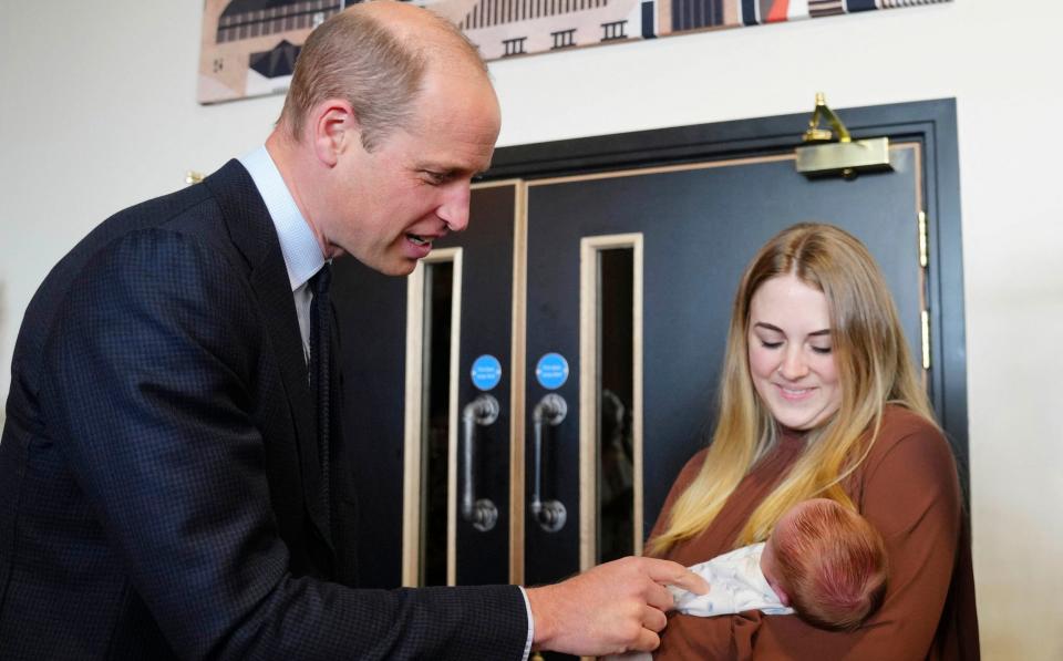 The Prince of Wales meets a young mother and her baby at the new outreach centre run by charity Betel UK